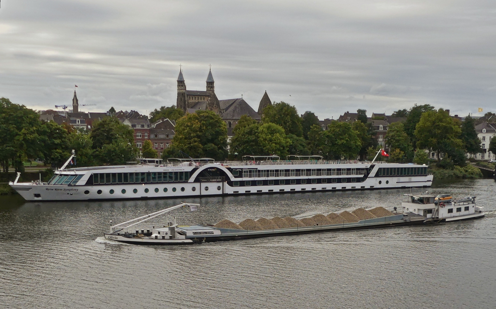 GMS Olivia 02329079, L 67 m, B 8,20 m, 1000 t, f�hrt auf der Maas zu Berg, am Hotelschiff Reise Riese Symphony, in Maastricht vorbei. 09.2025