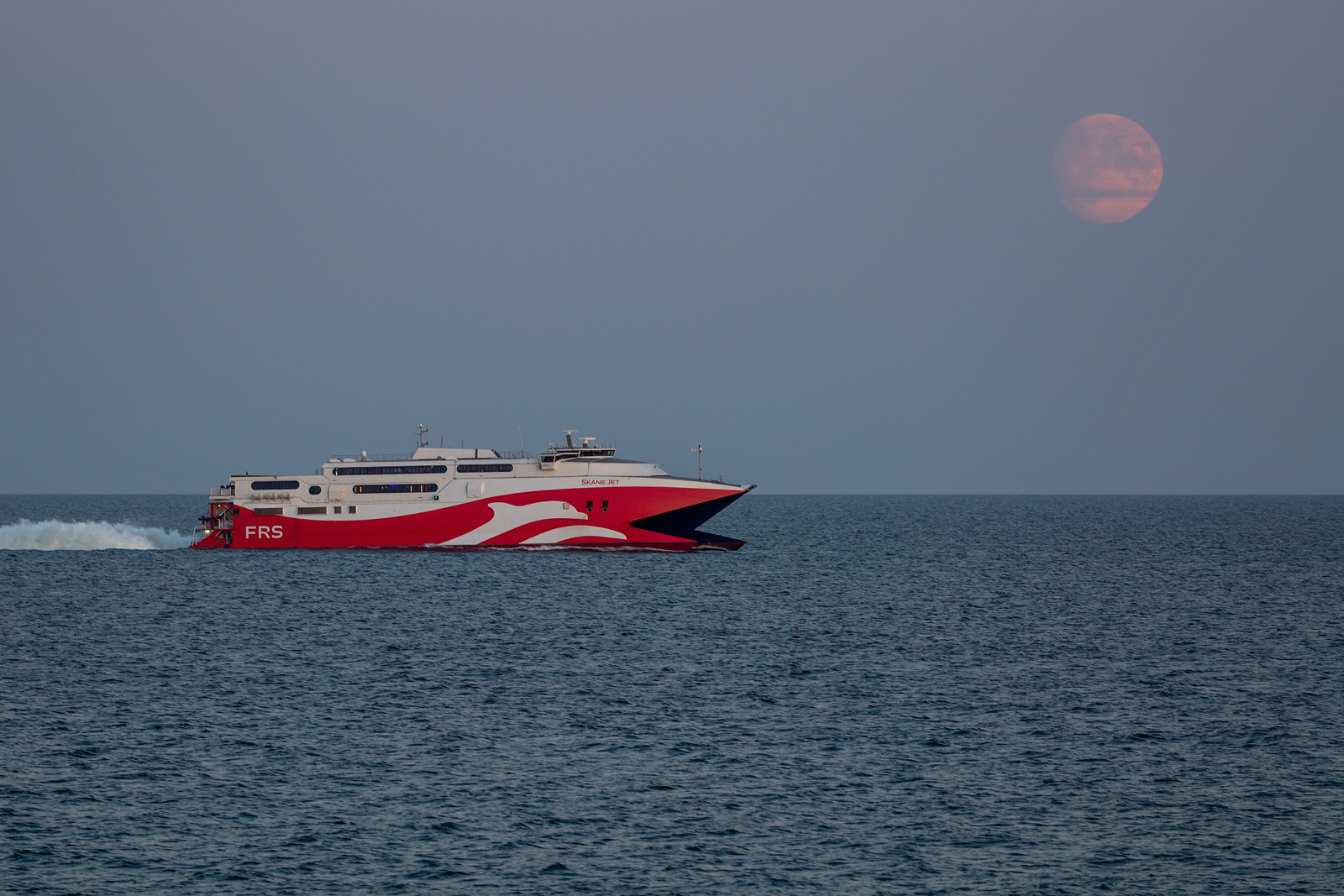 SKANE JET am frühen Abend mit dem zunehmenden Mond vor Rügen. - 07.10.2022