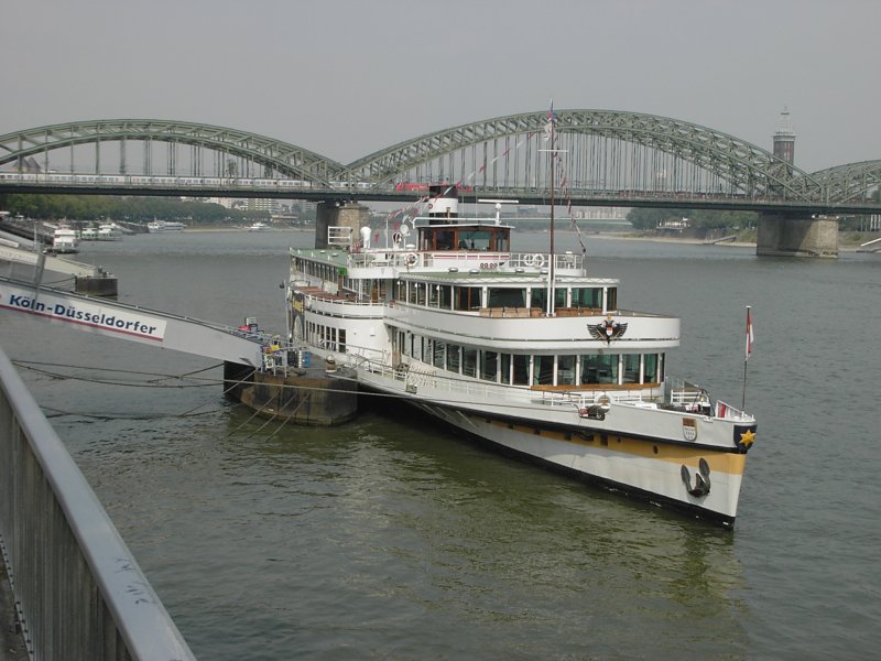 Ein Ausflugsschiff der Kln-Dsseldorfer vor der Rheinpromenade in Kln mit der Hohenzollernbrcke im Hintergrund am 21.08.2003.