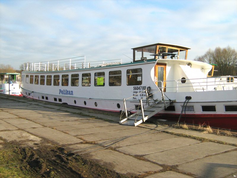 Hier eine Seitenansicht mit den daten des MS Pelikan (Stadthafen Henningsdorf bei Berlin, Oberhavel) ENR 5604780.  Abgestellte Autos und ein Zaun verhinderten eine Aufnahme von etwas weiter weg.