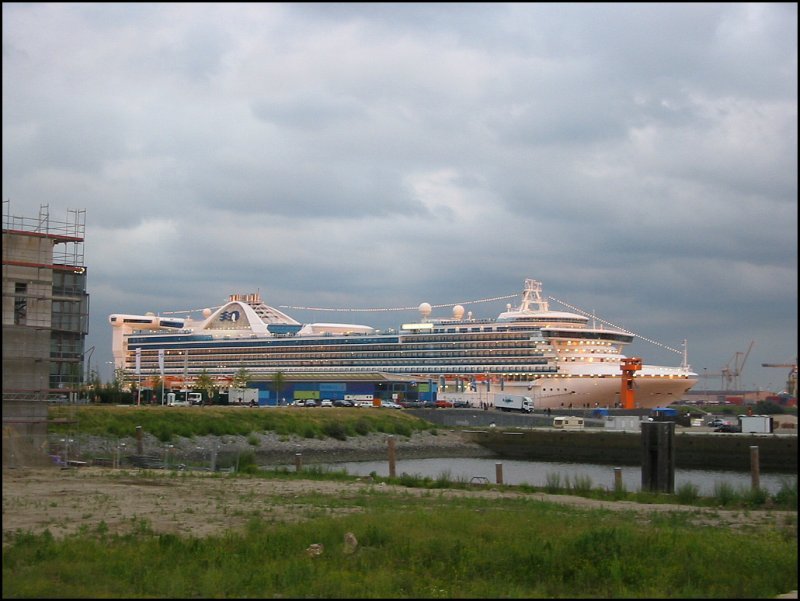 Im Juli 2005 hatte die  Golden Princess  am noch recht provisorisch wirkenden Kreuzfahrt-Terminal im Hamburger Hafen festgemacht. Das Gelnde ringsrum ist eine einzige Baustelle; dort soll die HafenCity entstehen, zu der auch ein reprsentatives Kreuzfahrt-Terminal gehren soll. Ich war bereits auf dem Rckweg Richtung Landungsbrcken, als die untergehende Sonne durch eine kleine Wolkenlcke das Schiff beleuchtete.