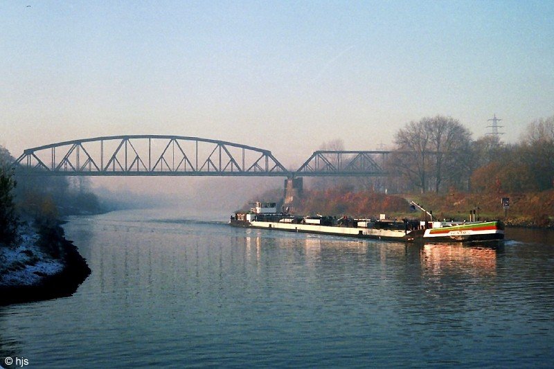 Rhein-Herne-Kanal in Essen-Dellwig (2. Dezember 1989). Die Verbreiterung des Kanalbettes an dieser Stelle erinnert daran, dass hier - etwa unterhalb der Brcke - frher die Schleuse Essen-Dellwig lag. Als Folge von Bergsenkungen hatte sich im Laufe der Zeit die Fallhhe von anfnglich 5 m soweit verringert, dass die Schleuse aufgegeben werden konnte.