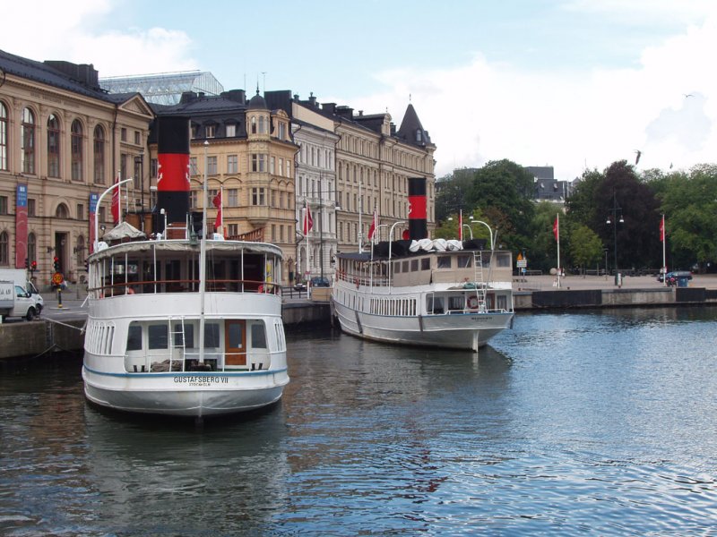 Stockholm-MS  Gustavberg  nach Gustavberg und  Waxholm III  nach Waxholm in Nybrokajen. Die beide Schiffe gehören zum Strömma Kanalbolaget.