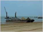 Ein beladener Schleppkahn am Strand bei der Hafeneinfahrt von Oostende.