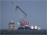 Die OLEG STRASHNOV (IMO 9452701) ist ein 183 m langes und 47 m breites Kranschiff. Die Hebefähigkeit beträgt 5.000 t, damit zählt die OLEG STRASHNOV zu den größten Schwimmkränen der Welt. Heimathafen ist Limassol (Zypern). 
Hier ist sie am 28.08.2016 beim Bau der Konverterplattform des Offshore-Windparks Wikinger nordöstlich von Rügen zu sehen. Rechts daneben liegt noch ein weiteres Schiff. 
Die Bildqualität/Schärfe lässt zwar zu wünschen übrig, es handelt sich um den Ausschnitt aus einer 400 mm-Teleaufnahme. Aber wann ist ein solches Schiff schon mal am Einsatzort zu sehen? 