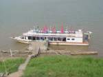 Niedrigwasser auf dem Mekong. In der Flumitte bei Nong Khai / Thailand ragt die Spitze eines Tempelchedi aus dem Wasser, zu dem viele glubige Thais mit diesem Motorboot bersetzen. 