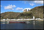 Vor der im Hintergrund sichtbaren Burg Katz oberhalb von St. Goarshausen kämpft sich das Motorschiff HÜNENKÖNIG am 27.02.2023 um 14.31 Uhr den Rhein strom aufwärts.