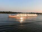 VIVALDI (ENI:01823464; L=110m; B=11,4m; 176Passagiere; Bj.2009) überholt im Raum Braila bei Sonnenaufgang sowie Donaubergfahrt ein Lastschiff; 230704