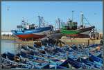 Hinter einer Armada an blauen Fischerbooten wurden zwei Fischkutter im Hafen der marrokanischen Küstenstadt Essaouira für Wartungsarbeiten aufgebockt.