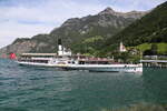 Der Raddampfer URI erreicht hier am 19.5.2025 den Hafen Flüelen am Vierwaldstätter See. Im Hintergrund die Pfarrkirche Herz Jesu.
