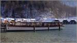 Die MARIA ALM gehrt zur Flotte der 17 Elektroboote, mit denen auf dem Knigssee die Personenschifffahrt betrieben wird. Sie liegt hier am Anleger Seelnde. Dahinter sind die Bootsschuppen zu sehen. 18.01.2012