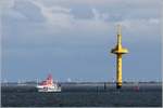 Der in Bremerhaven stationierte Seenotrettungskreuzer HERMANN RUDOLF MEYER liegt beim Radarturm Wurster Arm in der Außenweser vor Anker. Links vom gelben Radarturm ist im Hintergrund der weiße, 230 m hohe Fernmeldeturm (Friedrich-Clemens-Gerke-Turm) von Cuxhaven zu sehen. 10.09.2019