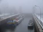 Bei ziemlich dichtem Nebel liegen das Frachtschiff BERTA und ein Schubverband von Hamburg kommend in der Geesthachter Schleuse; 07.12.2010  
