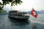 Schweiz - Die schweizer Fahne flattert im Wind und die MS Rigi entfernt sich langsam von der Anlegestelle Vitznau am Vierwaldstätter See. 1.5.2007