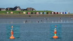 Die beiden Fahrwassertonnen, Föhrer Ley 34 und Amrum Mole 26, sind nur Dekoration in diesem Bild. (Bildmontage). Im Bildhintergrund der Strand von Dagebüll bei ablaufenden Wasser. Probleme bereiten in diesem tideabhängigen  Fahrwasser der W.D.R. (Wyker Dampfschiffs-Reederei) immer wieder Schlickbildungen. Zur Fahrwasserpflege werden dann Spezialschiffe eingesetzt die die Untiefen beseitigen und immer  die Handbreit Wasser unter dem Kiel  garantieren. Konventionell wird die Verschlickung mit einem Saug/Hopperbagger abgetragen. Ein zweites Verfahren ist die Wasserinjektion. Dabei wird der Schlick mit einem Wasserstrahl dicht über dem Meerboden verflüssigt. Die Arbeiten werden bei Hochwasser ausgeführt. Dabei nimmt automatisch das abfließende Ebbewasser den Schlick mit der Strömung aus dem Fahrwasser oder dem gefährdeten Hafenbecken. Foto: Spätsommer 2014