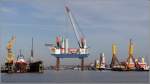 Hafenszene aus dem Kaiserhafen 3 in Bremerhaven.
Links ist ein Schwimmdock zu sehen, in dem ein Schlepper überholt wird. 
In der Bildmitte hat sich das Errichterschiff THOR (IMO 9577147) aufgejackt um Turmsegmente und Generatorgondeln für Offshore-Windenergieanlagen zu laden. Diese zu übernehmenden Turmsegmente befinden sich rechts davon auf der Barge STRALSUND, die von einem Schlepper in Position gehalten wird.
Ganz rechts sind zwei ca. 60 m hohe Tripods zu sehen, die als Gründungsstrukturen für Offshore-Windenergieanlagen verwendet werden.
03.02.2013 