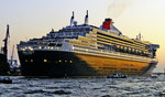 QUEEN MARY 2 verlässt den Hafen von Hamburg im Licht der untergehenden Sonne.