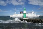 Stürmische See und Sonnenschein herschen an der Westmole von Warnemünde während im Hintergrund die Fähre von Gedser nach Rostock (Kronprins Frederik) vorbeifährt.