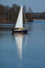 Kein Eissegler. Obwohl der Kapitän sein Segelboot hier an der Havel dicht an der  Eisgrenze  entlang manövriert. Die Grenze der Eisschicht ist im unteren drittel des Bildes zu erkennen. Sie verläuft durch die Mitte des Segels im Spiegelbild. Foto:04.03.2013   