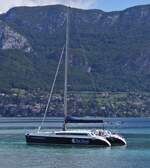 1 Master Katamaran liegt unweit vom Ufer auf dem See von Annecy vor Anker. 09.2022