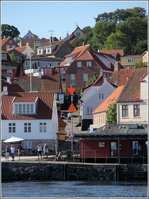 Die Richtfeuer für die Ansteuerung des Hafens von Gudhjem auf Bornholm sind hier gut zu erkennen. Es sind die beiden gegeneinandergerichteten, in signalrot gestrichenen Dreiecke, die jeweils oberhalb mit Leuchtfeuer versehen sind.  Die baulichen Gegebenheiten machten es hier erforderlich, das Oberfeuer in der nach oben führenden Straße zu errichten. Das Unterfeuer steht neben dem Schuppen am Kai. 25.08.2016