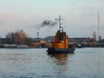 Schlepper  NOK 1  / Kiel wartet vor der Schleuse Holtenau, die durch eine Beschädigung nur einseitig befahren werden kann. Die Rauchfahne im Hintergrund stammt von der  Lantau Arrow . 22.02.2018, Kiel, Nord-Ostsee-Kanal