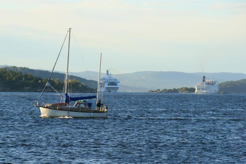 Während ein Segler den Sportboothafen von Drøbak verlässt, begegnen sich im Oslofjorden die F/S  Crown of Scandinavia  und die F/S  Stena Saga . Drøbak, 17.09.2009
